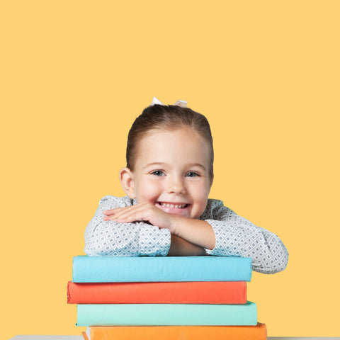 Menina sorridente, apoiada em livros escolares